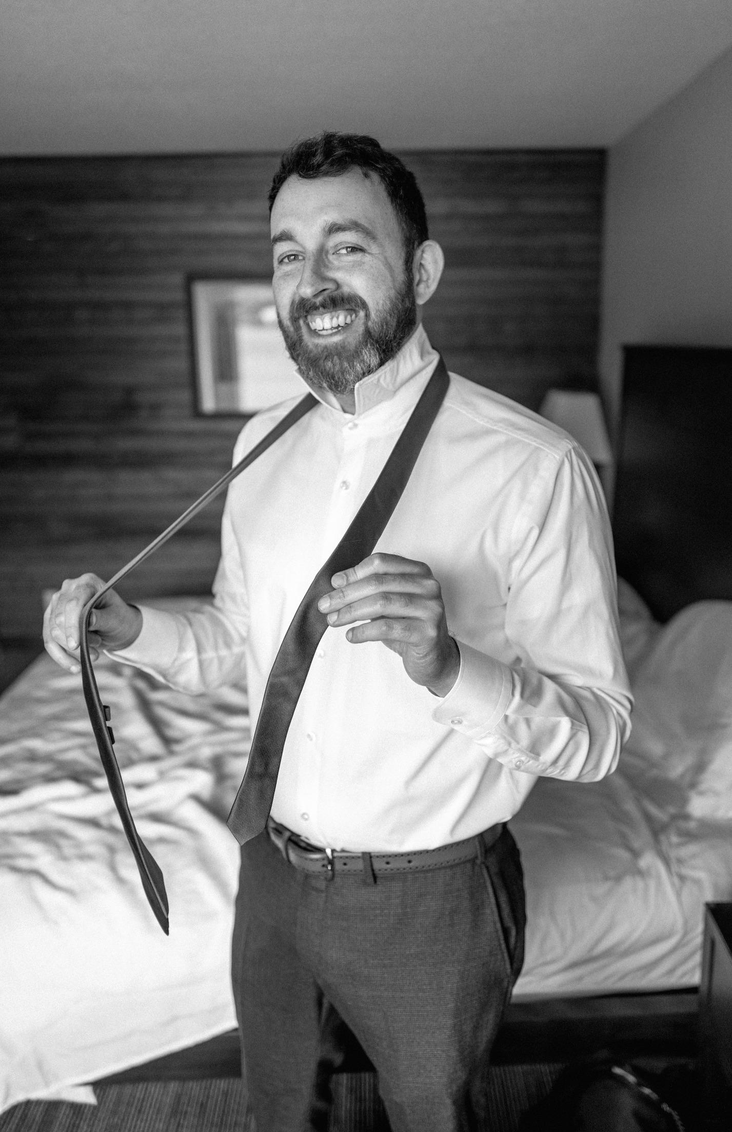 Black-and-white portrait of Leon smiling while adjusting his tie